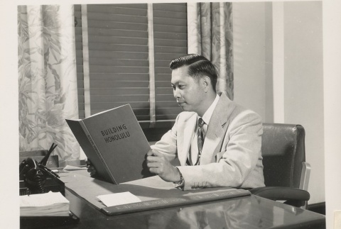 A Honolulu Chamber of Commerce treasurer reading at his desk (ddr-njpa-2-241)