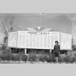 Female soldier standing in front of the Honor Roll at Minidoka (ddr-fom-1-398)