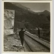 Soldier by railroad tracks pointing to a mountain (ddr-densho-201-108)