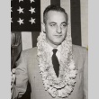 Man posing with leis in front of a flag (ddr-njpa-2-276)