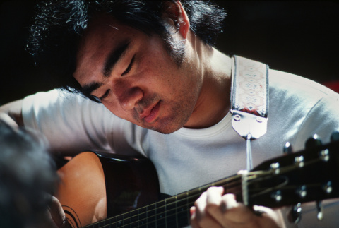 Ted Hasegawa playing guitar at morning watch (ddr-densho-336-1319)