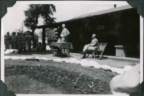 Man speaking in front of camp building (ddr-ajah-2-498)
