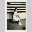 Woman seated in front of wall with American flag (ddr-densho-475-345)