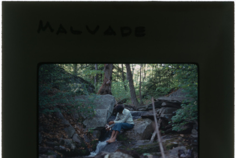 A man sitting by a stream at the Malavade project (ddr-densho-377-1108)