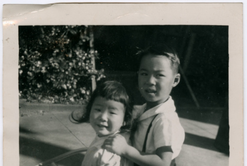 Masako Takahashi riding tricycle, with Norman (?) (ddr-densho-426-968)
