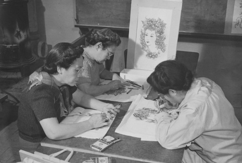Three students doing steamed crayon work for tablecloths and wall hangings in adult crafts class at Granada incarceration camp (ddr-csujad-14-41)