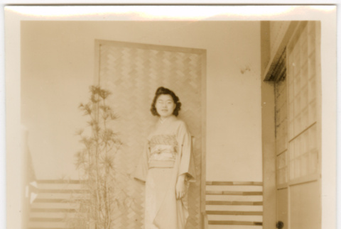 Tomoye (Nozawa) Takahashi in kimono standing in front of screen (ddr-densho-426-2140)
