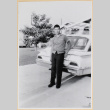 Young man standing by car in driveway (ddr-densho-522-25)