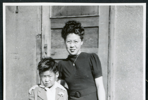 Photograph of Mrs. Moroika and son Ned posing in front of a door at Cow Creek Camp in Death Valley (ddr-csujad-47-128)