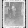 Man in uniform standing on steps of house with man and woman (ddr-densho-434-408)