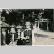 Woman with camera standing by stone lanterns (ddr-densho-426-1073)