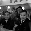 Two men sitting at counter, woman standing behind them (ddr-densho-426-1761)