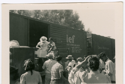 Two men loading train car in front of crowd (ddr-densho-475-395)
