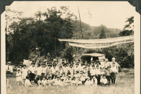 Group of children with U.S. flags posing in field (ddr-densho-483-519)