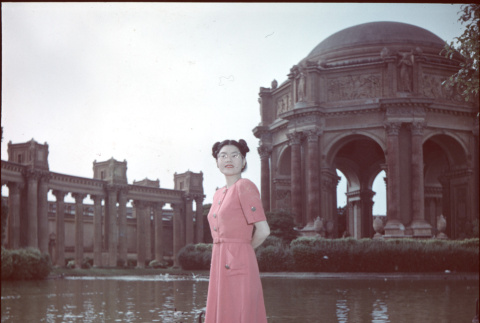 Woman in pink dress standing by pond by Palace of Fine Arts (ddr-densho-426-939)