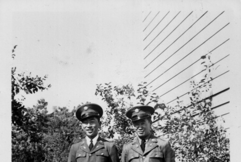 Two men standing on path outside building (ddr-ajah-2-769)