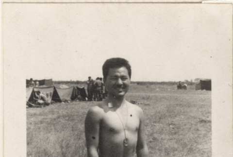 Shirtless man standing in field near tents (ddr-densho-466-251)