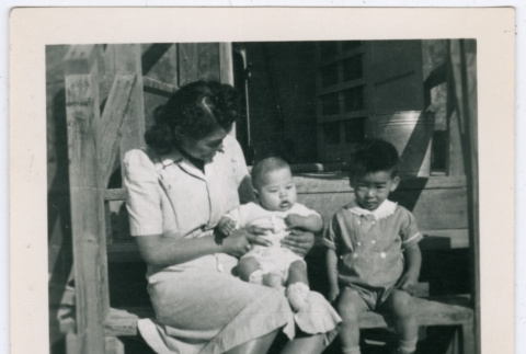 Woman with baby and boy on barracks steps in Minidoka (ddr-densho-543-2)