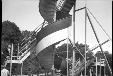 Two girls on corkscrew slide in park (ddr-densho-426-960)
