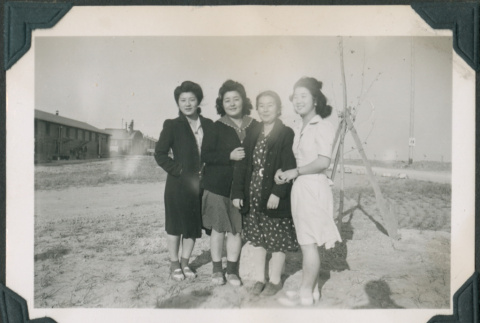 Four women in camp with barracks in background (ddr-densho-483-1099)