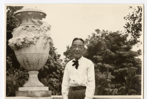 Man posing next to a statue (ddr-densho-542-795)