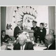 Group of men around speakers table with banner in background (ddr-ajah-2-17)