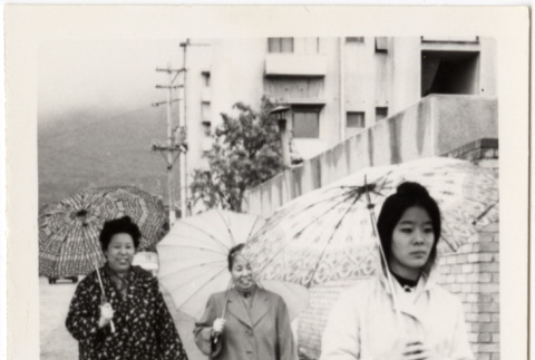Masako Takahashi with two women walking in rain (ddr-densho-426-230)