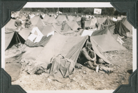 Man sitting outside tent with tents in the background (ddr-ajah-2-263)