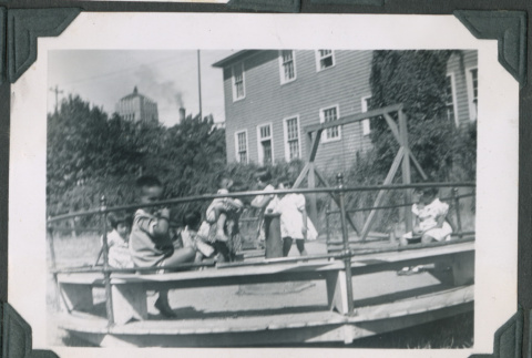 Photo of children on a playground merry-go-round (ddr-densho-483-921)