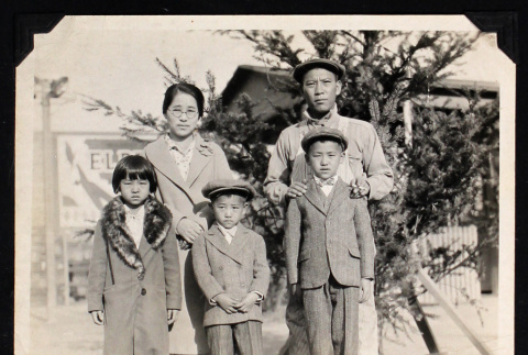 Family of five poses in front of an evergreen tree (ddr-densho-404-90)