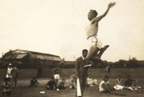 Chuhei Nambu practicing the long jump while others look on (ddr-njpa-4-1352)