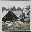 Man sitting next to tent with gear (ddr-densho-434-463)