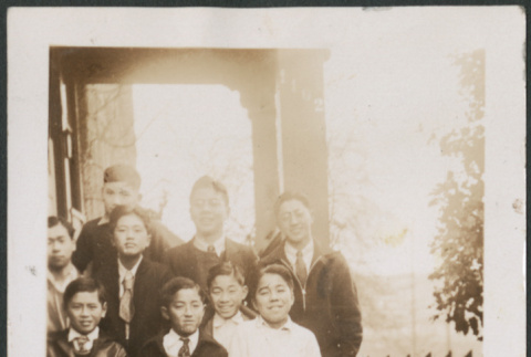 Group of men and boys posing for photo on porch (ddr-densho-483-564)
