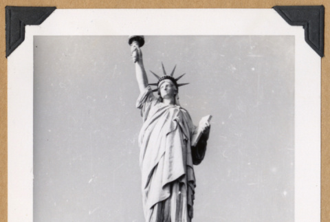 Man posing beside the Statue of Liberty (ddr-densho-542-335)