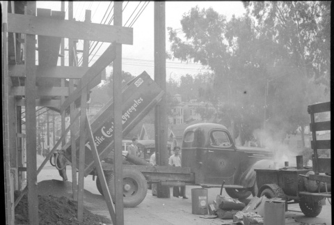 Pacific Coast Aggregates dump truck unloading at construction site (ddr-densho-426-1768)