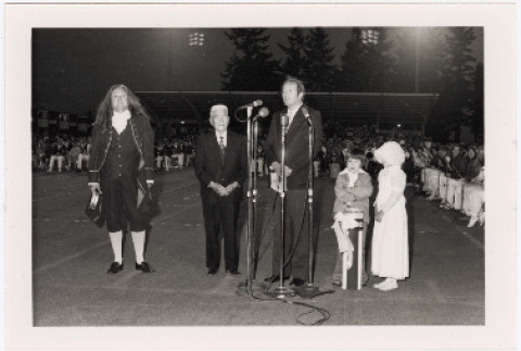 Photo of man dressed as Benjamin Franklin with men standing at microphone (ddr-densho-122-796)