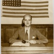 Man seated at a desk holding a gavel (ddr-njpa-2-582)