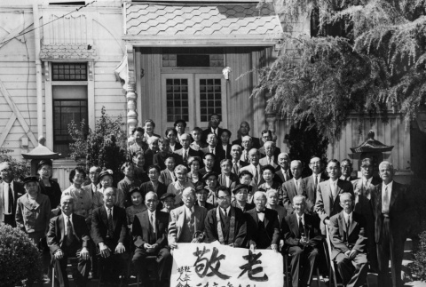 Group photo outside building, holding banner in Japanese (ddr-ajah-3-186)
