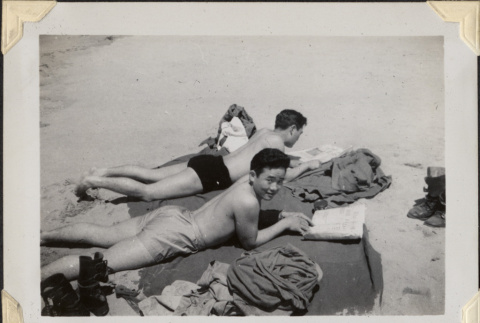 Two men laying on blanket on beach (ddr-densho-466-865)