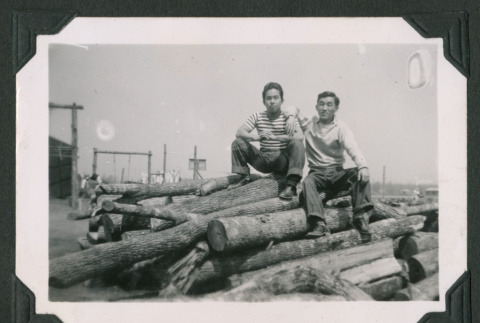 Two men sitting on a log pile (ddr-densho-471-90)
