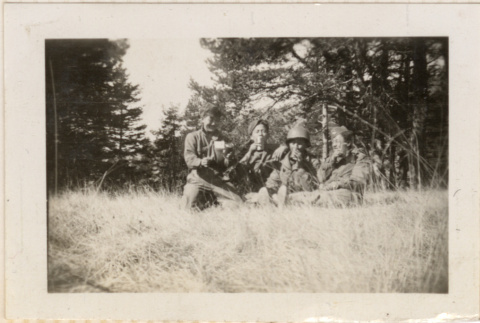 Four men sitting in tall grass, drinking (ddr-densho-466-267)