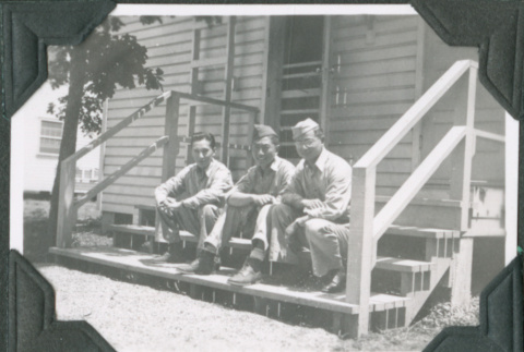 Three men sitting on steps of barracks.  Joe Iwataki in center (ddr-ajah-2-395)
