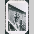 Man with baby on his shoulders outside barracks (ddr-densho-483-1095)