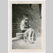 Photo of a child sitting on a ledge with a drum (ddr-densho-483-744)