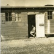 Woman sitting in the doorway of her Assembly Center barracks (ddr-densho-22-447)