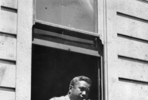 Man on telephone leaning out window (ddr-ajah-6-417)