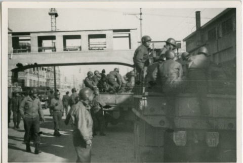 Soldiers driving through the street on military flatbed trucks (ddr-densho-201-55)