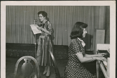 Woman playing piano with another woman standing at microphone (ddr-densho-316-338)