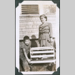 Photo of Kenji Ima and Tsumu Fukuyama with a dog in a crate in a wagon (ddr-densho-483-1245)