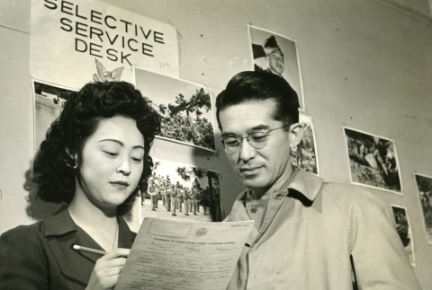 Military recruit filling out Selective Service paperwork with a woman (ddr-densho-22-493)
